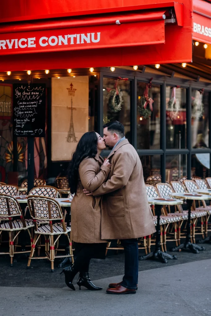 A couple kissing in front of a Parisian café